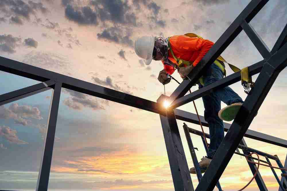 construction worker welding on a roof to build a residential or commercial fixture to protect workers and safety gear using ppe