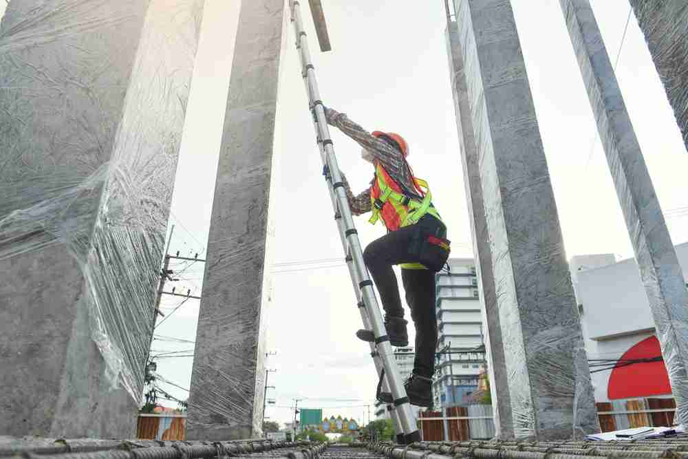 construction worker climbing a ladder to reach top of building safely using osha safety standards and atlantic equipment